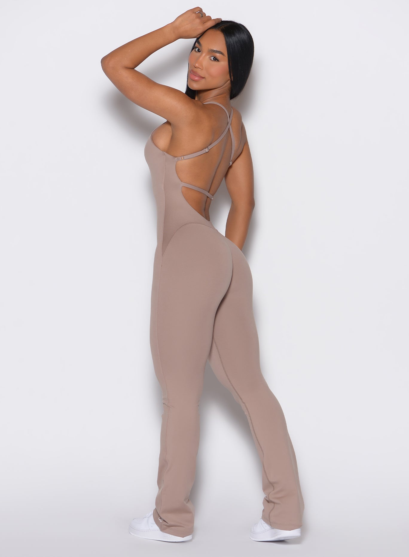 Left side profile view of a model touching her hair wearing the Bombshell Bunny Bodysuit in Clay color.