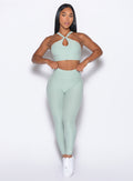 front profile view of our model adjusting the waistband wearing the Bombshell Bunny Leggings in soft aloe color