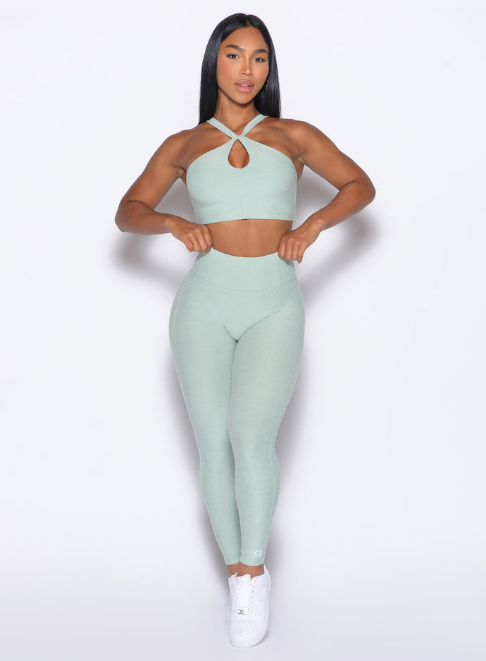 front profile view of our model adjusting the waistband wearing the Bombshell Bunny Leggings in soft aloe color