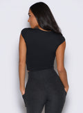 back profile view of a model facing to the left side wearing the Bombshell Era Tee in black color 