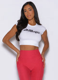 front profile view of a model with both hands on her hips wearing the Bombshell Era Tee in white color 