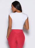 back profile view of a model facing to the left side wearing the Bombshell Era Tee in white color 