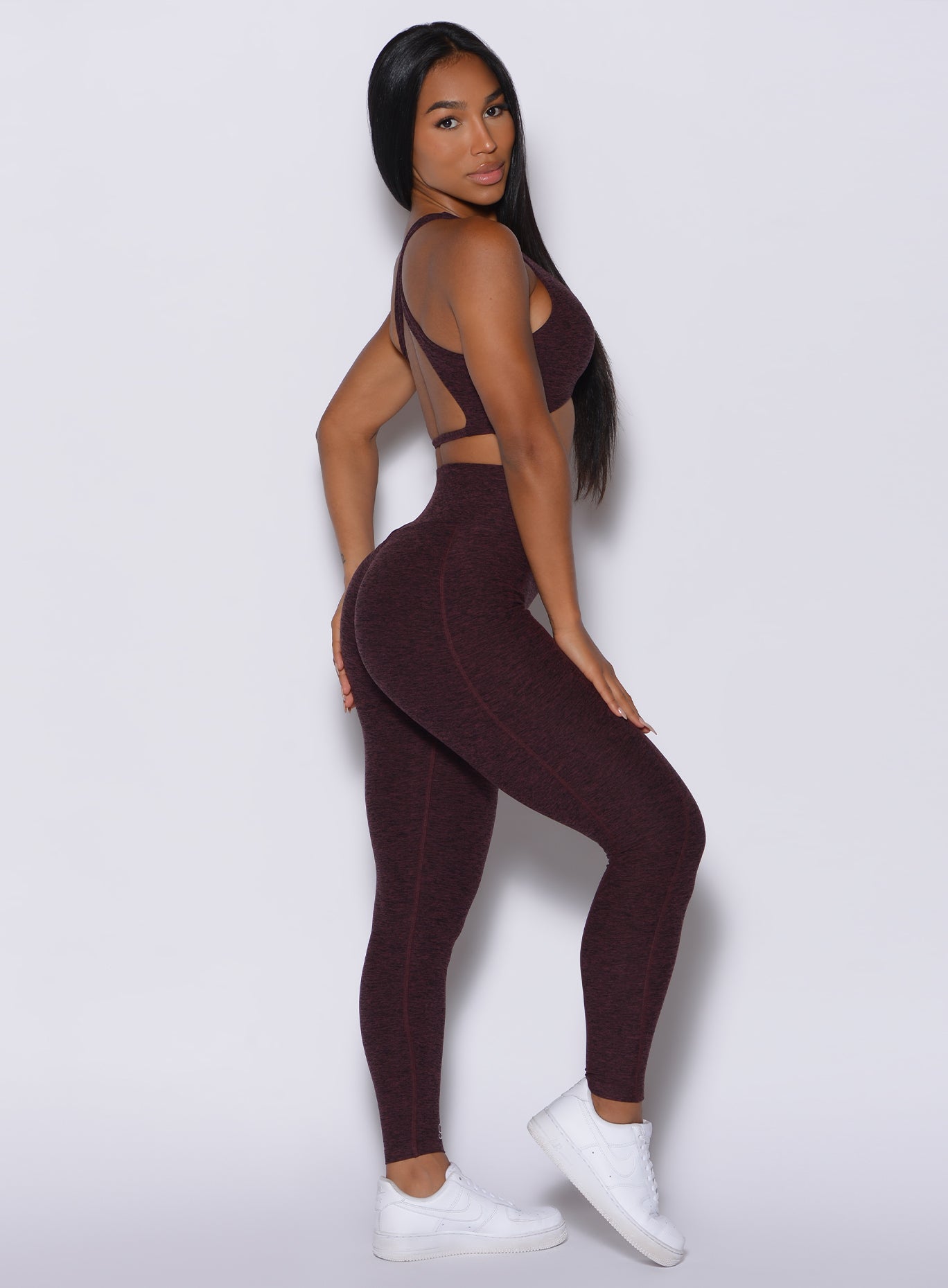 Right side profile view of a model in our Brazilian Contour Leggings in port color and a matching sports  bra