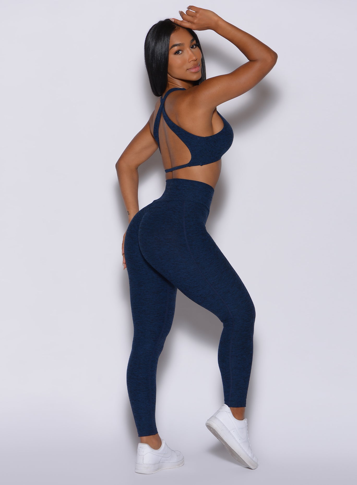 Right  profile view of a model in our Brazilian Contour Leggings in sapphire blue color and a matching ace sports bra