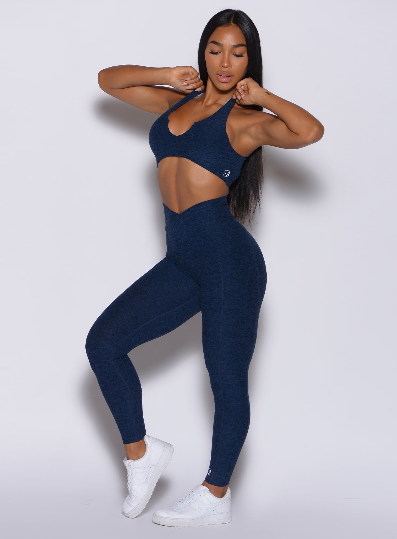  profile view of a model posing in our Brazilian Contour Leggings in sapphire blue color and a matching bra