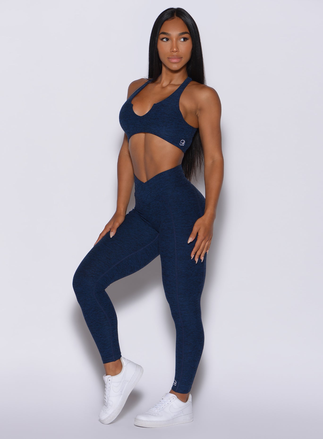 Left side  profile view of a model angled to her left wearing our Brazilian Contour Leggings in sapphire blue color and a matching bra