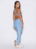 back right side profile view of a model looking over her shoulder wearing the Built Leggings in Blue mist color