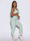 a right side shot of a model holding her hands in front wearing the built leggings in soft aloe color