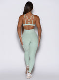 a rear perspective of a model wearing the built leggings in soft aloe color