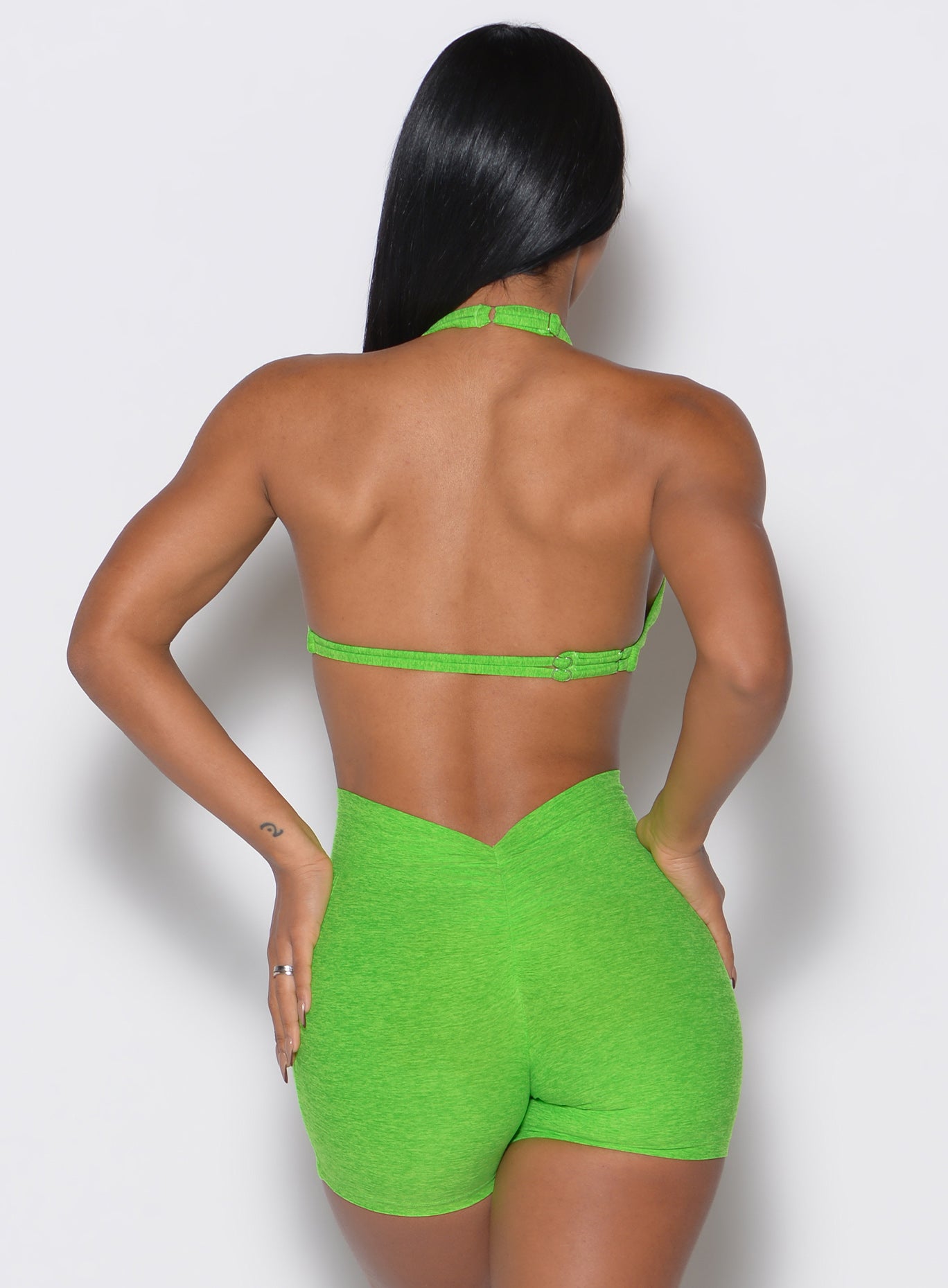 back profile view of a model wearing our butterfly sports bra in neon lime green color along with the matching shorts