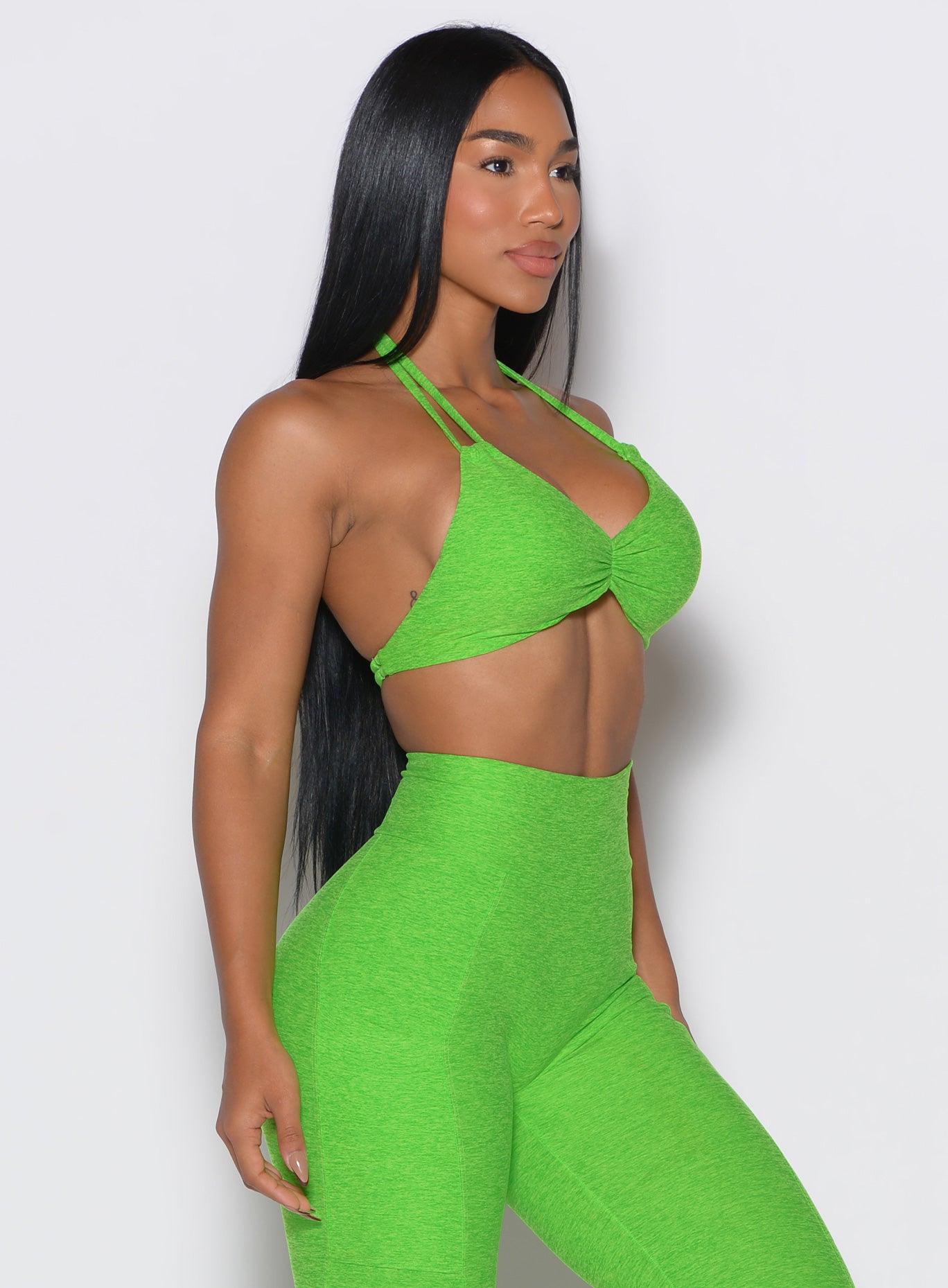 right side profile view of a model wearing our butterfly sports bra in neon lime green color along with the matching leggings