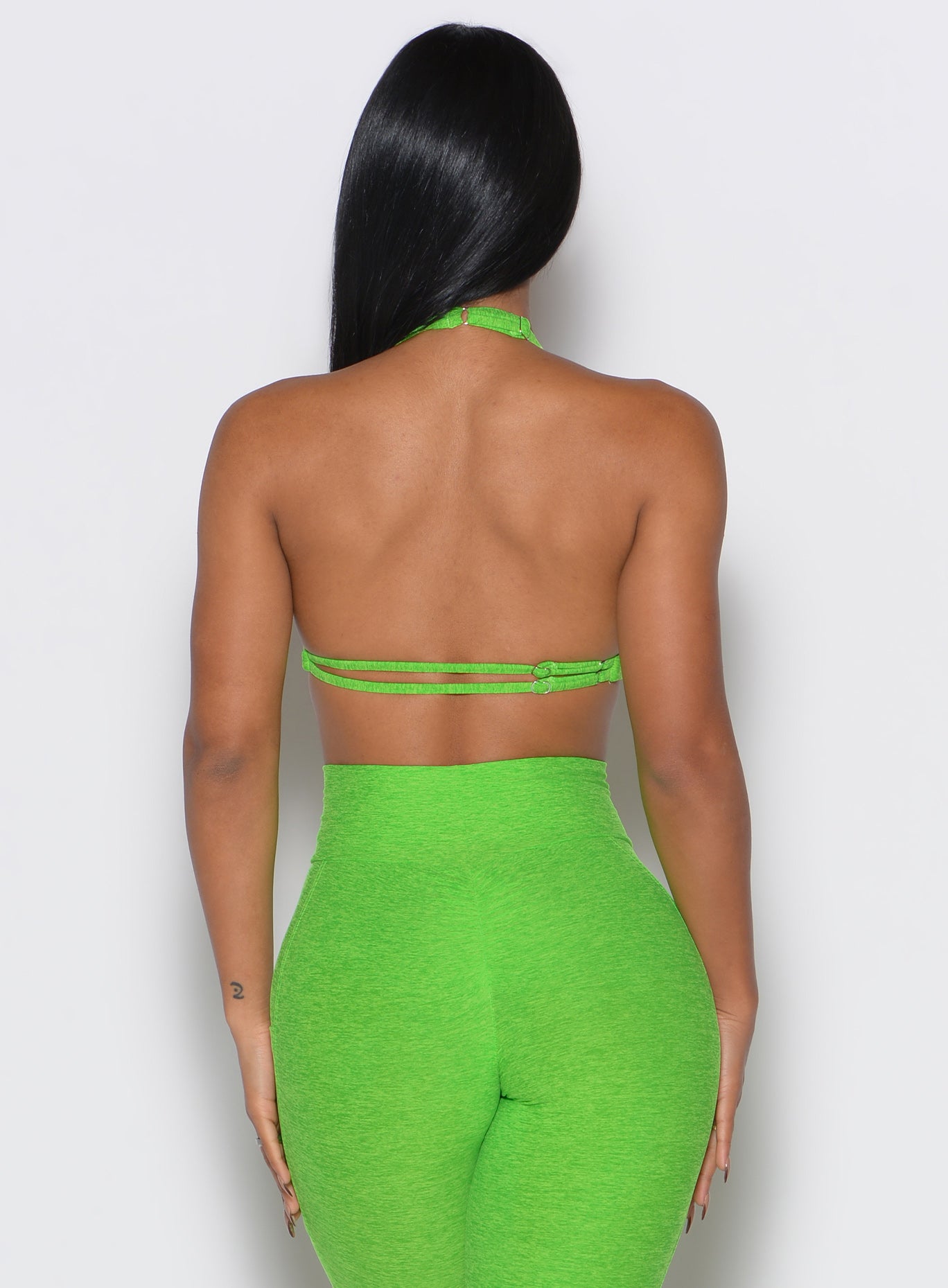 back profile view of a model wearing our butterfly sports bra in neon lime green color along with the matching leggings 