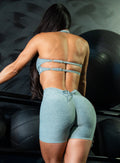 back profile view of a model in indoors wearing the Curvemax Shorts in sea moss color