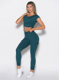 front left side profile view of a model with one hand on the waistband wearing the Cargo Edge Leggings in dark sea color