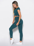 left side profile view of a model wearing the Cargo Edge Leggings in dark sea color