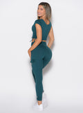 back left side profile view of a model looking over her shoulder wearing the Cargo Edge Leggings in dark sea color