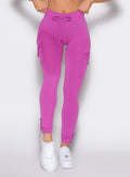 close up front profile view of a model with both hands on the waistband wearing the Cargo Edge Leggings in hyper violet color
