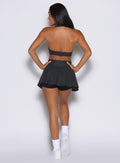 back profile view of a model facing to the left side wearing the Champion Skort in Charcoal color 