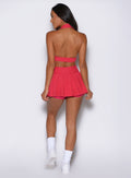 back profile view of a model facing to the left side wearing the Champion Skort in Victory Ruby color 