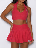 close up front view of a model with one hand on her waist wearing the Champion Skort in Victory Ruby color 