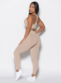 left side profile view of a model wearing our cheeky seamless leggings in Timeless Taupe color along with the matching bombshell bra