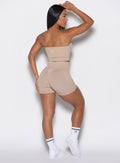 back profile view of a model facing to her right wearing our cheeky seamless shorts in timeless taupe color along with a matching bandeau