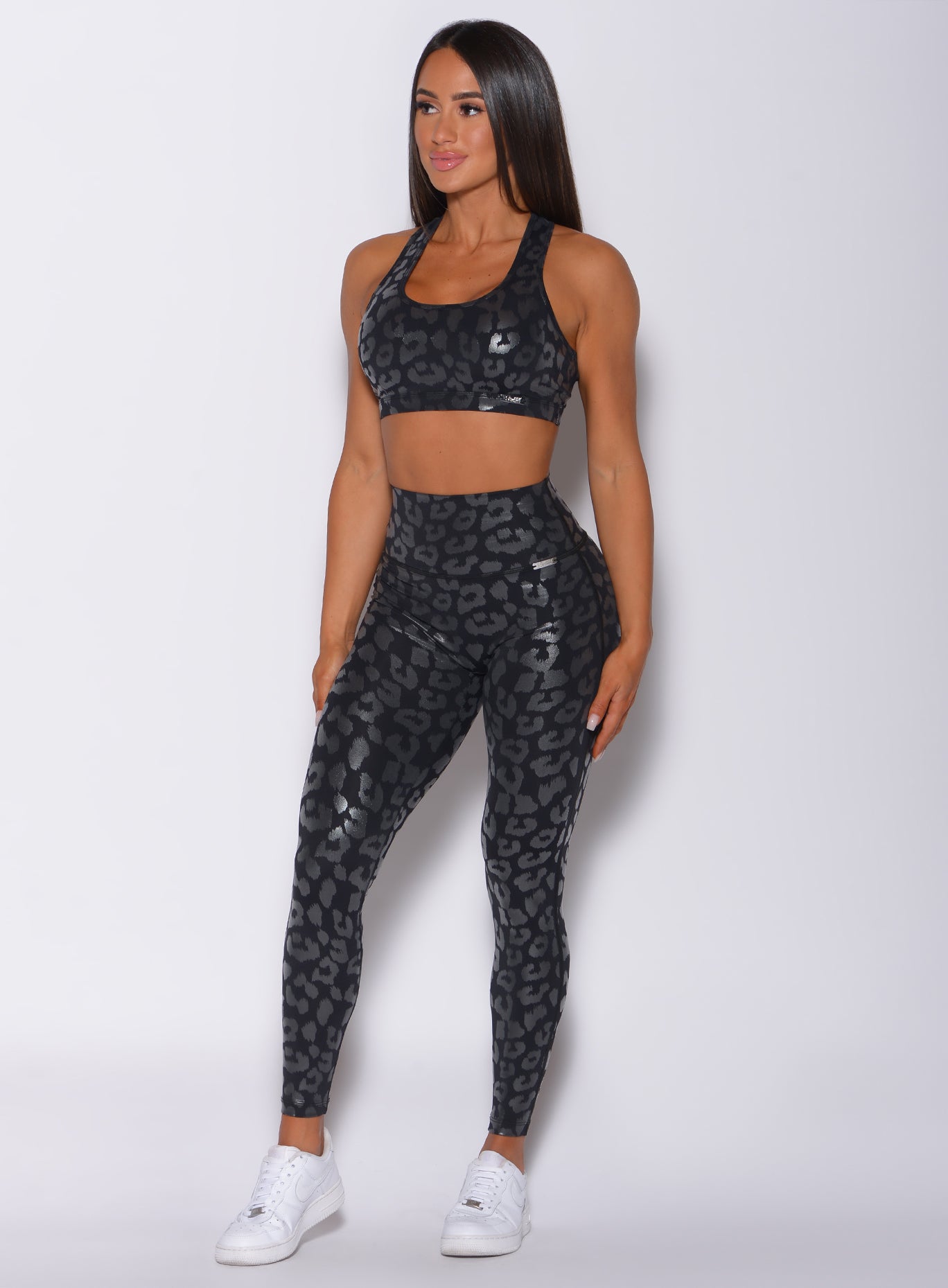 Front profile view of a model wearing our shine leopard leggings in Black Leopard color along with the matching sports bra 