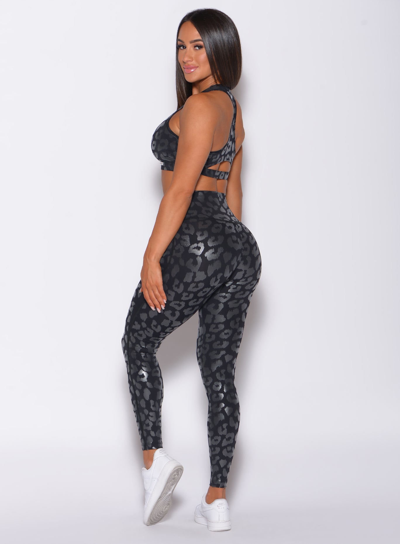 left side profile view of a model wearing our shine leopard leggings in Black Leopard color along with the matching sports bra 