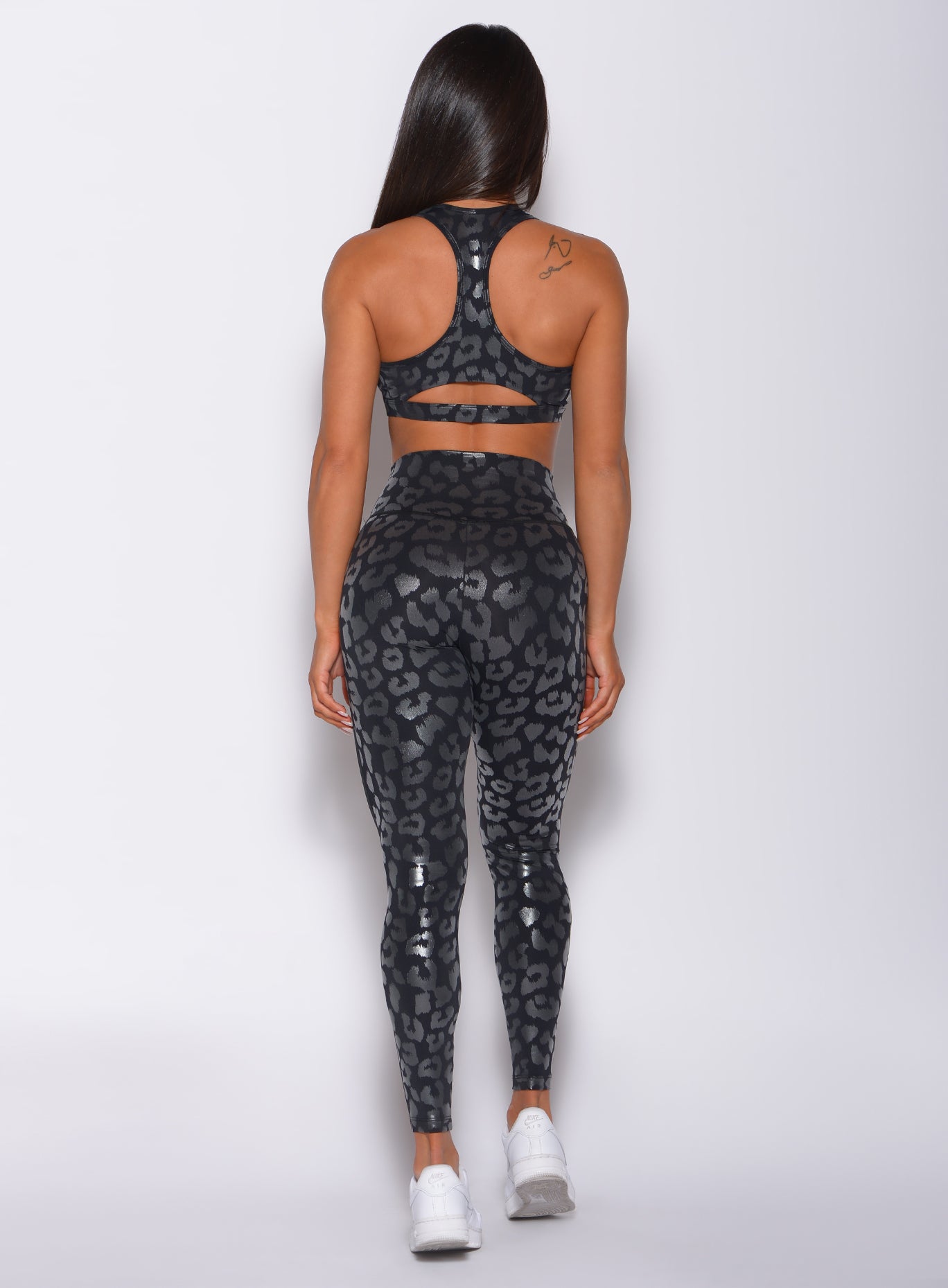 back profile picture of a model wearing our shine leopard leggings in Black Leopard color along with the matching sports bra