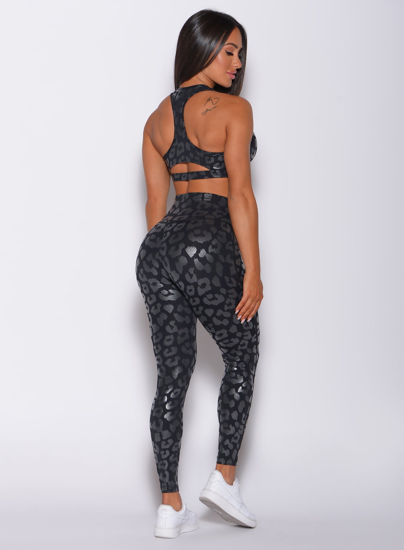 Back  profile view of a model wearing our shine leopard leggings in Black Leopard color along with the matching sports bra
