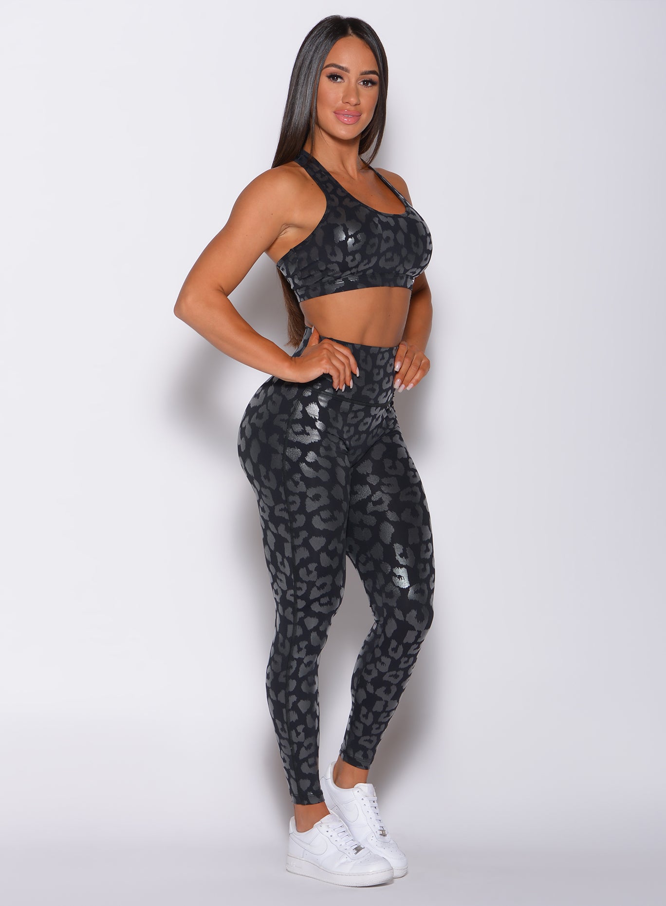 right side  profile view of a model facing to her right wearing our shine leopard leggings in Black Leopard color along with the matching sports bra