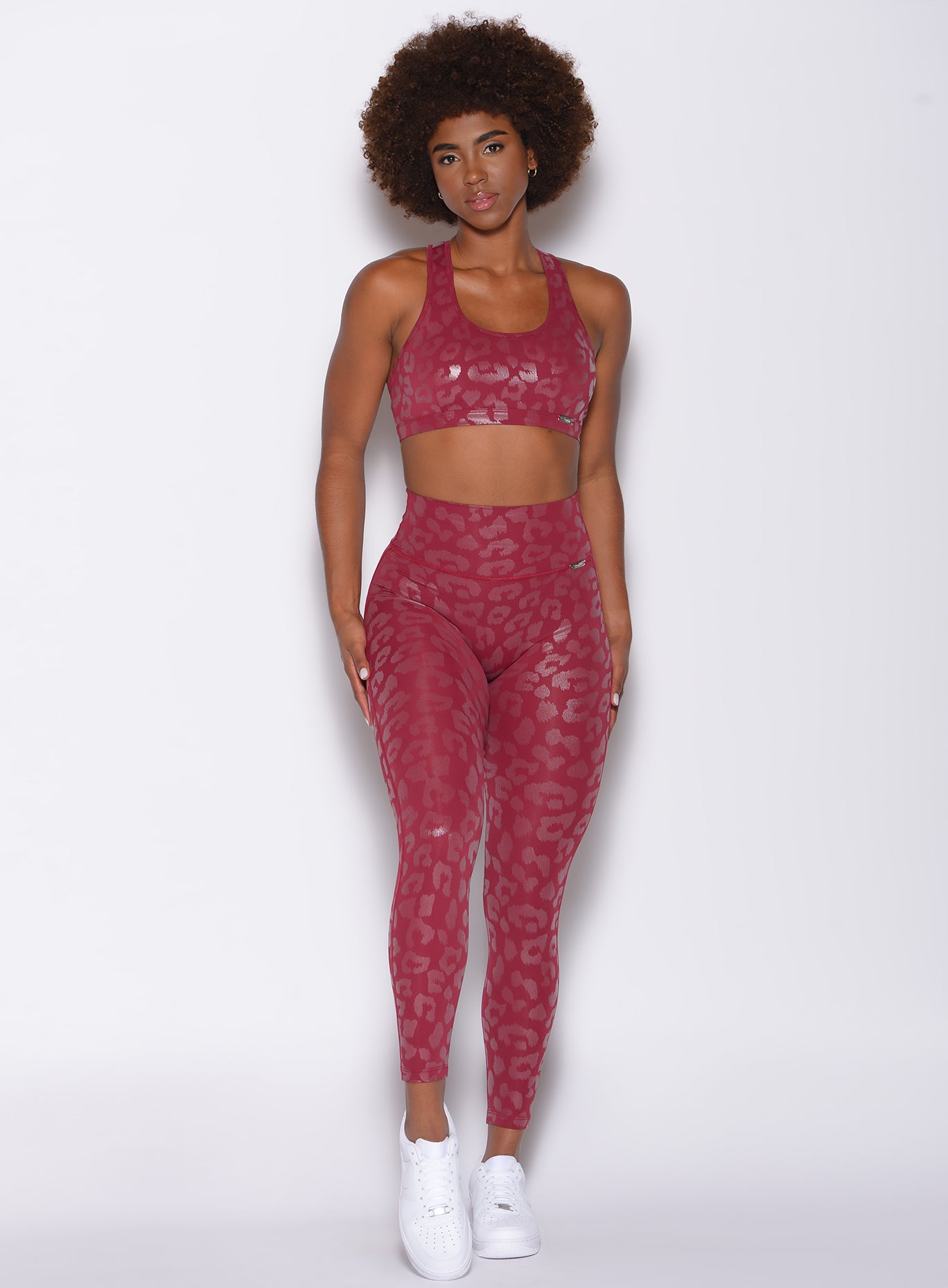 front profile view of a model in our shine leopard leggings in Raspberry Leopard color and a matching sports bra