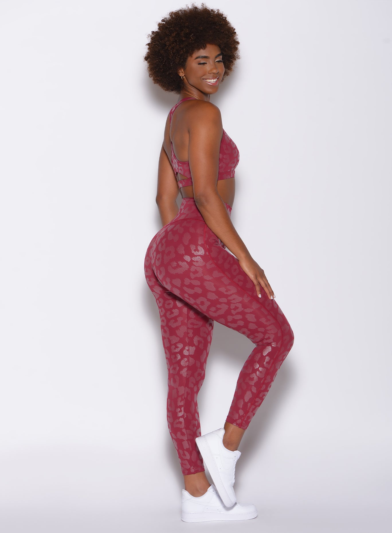 right side profile view of a model facing to her right wearing our shine leopard leggings in Raspberry Leopard color along with a matching sports bra