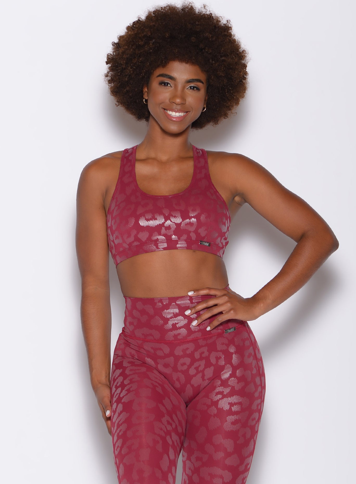front profile view of a model with her left hand on waist  wearing our shine leopard bra in Raspberry Leopard color along with the matching leggings