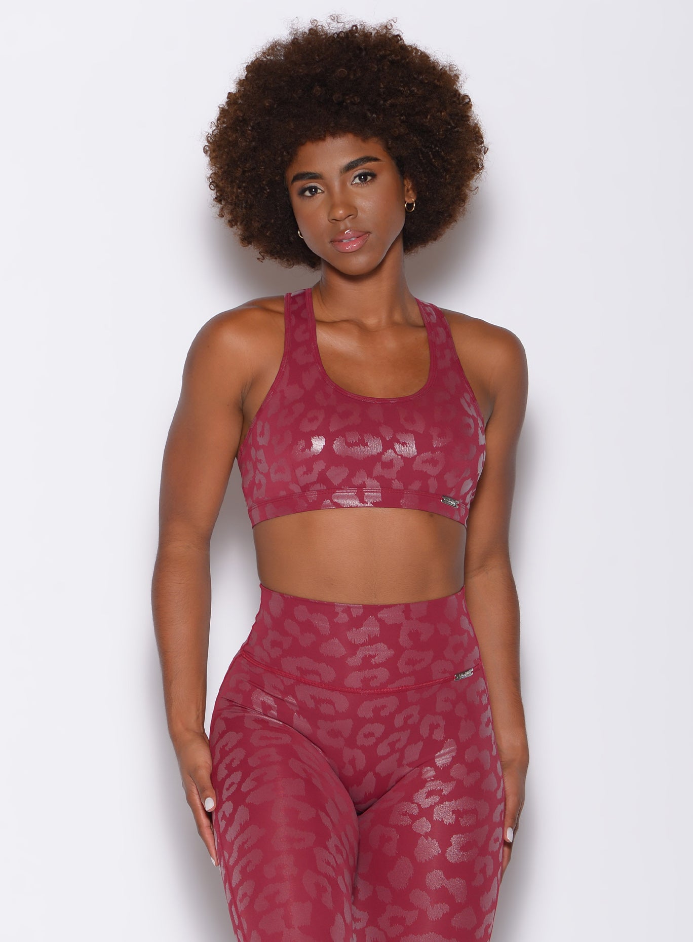 front profile view of a model facing forward wearing our shine leopard bra in Raspberry Leopard color along with the matching leggings