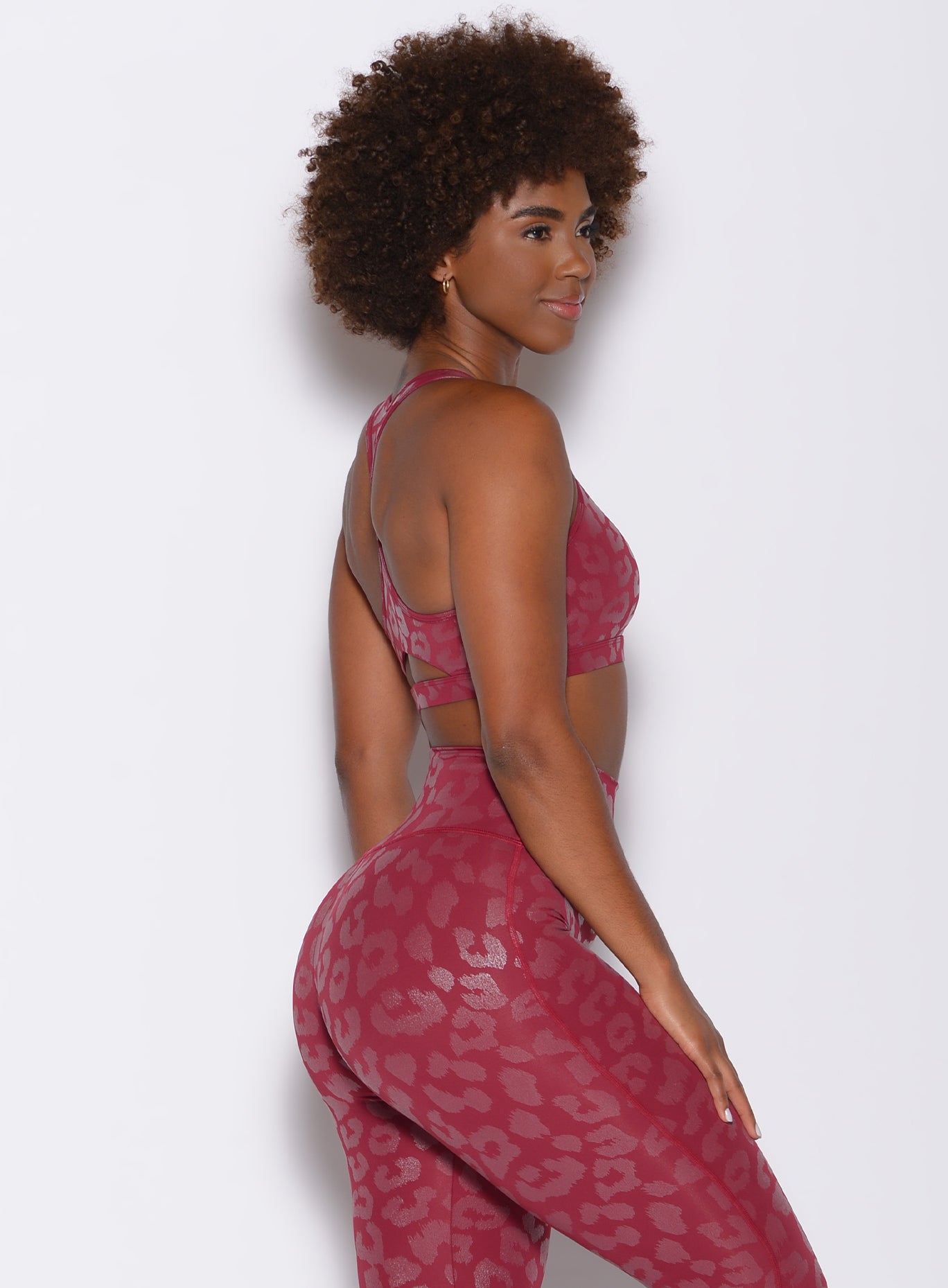 right side profile view of a model wearing our shine leopard bra in raspberry leopard color along with the matching leggings 