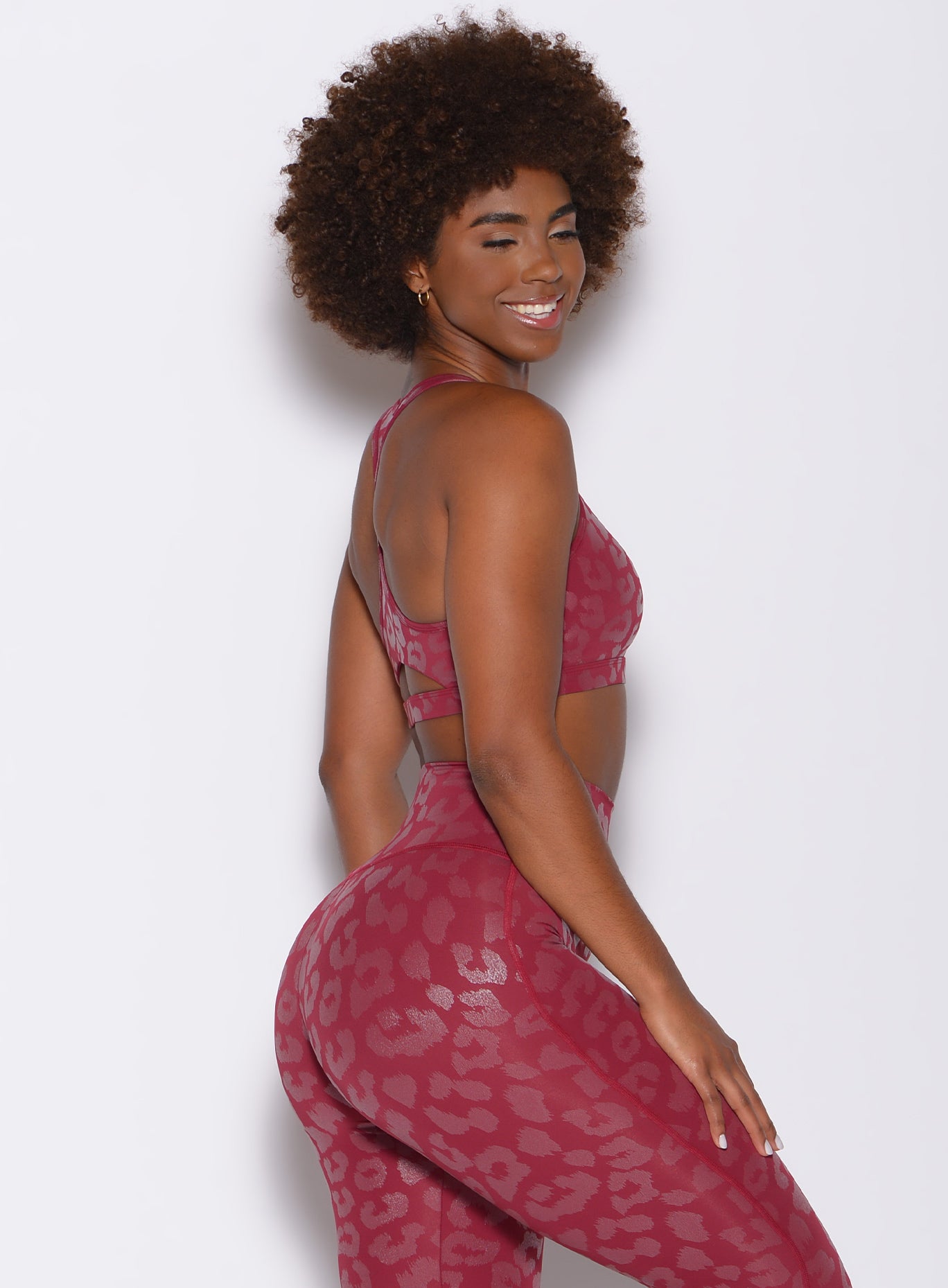 right side profile view of a model wearing our shine leopard bra in Raspberry Leopard color along with the matching leopard print leggings