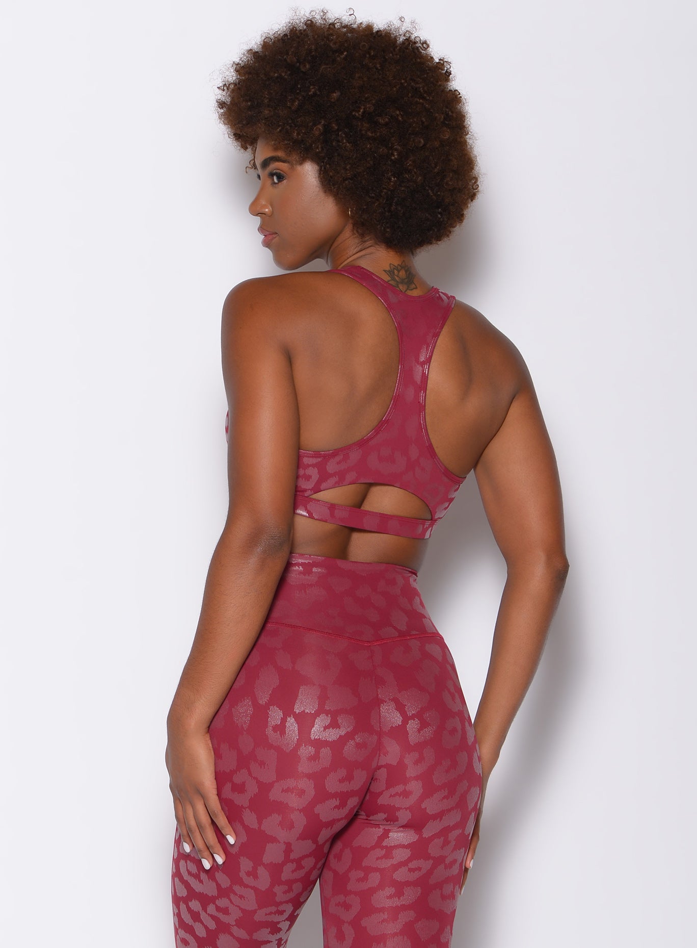 Back profile view of a model wearing our shine leopard bra in Raspberry Leopard color along with the matching leggings