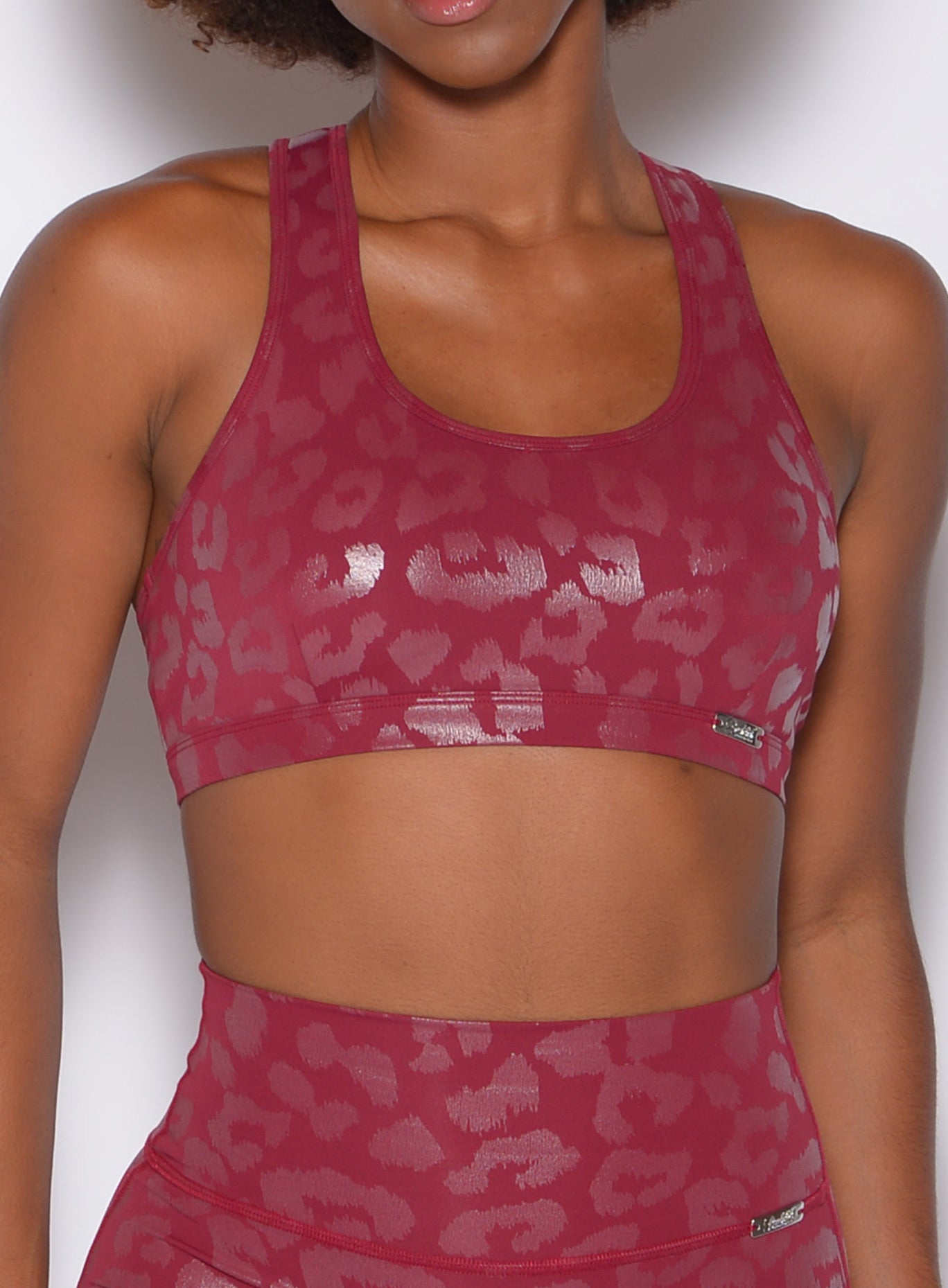 Zoomed in front profile view of a model wearing our shine leopard bra in Raspberry Leopard color along with the matching leggings