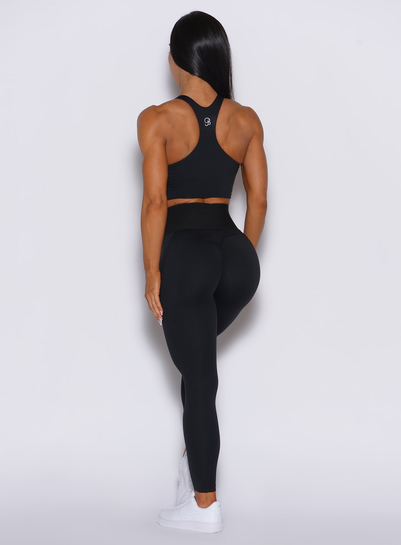 Back profile view of a model in our black cincher leggings and a matching top