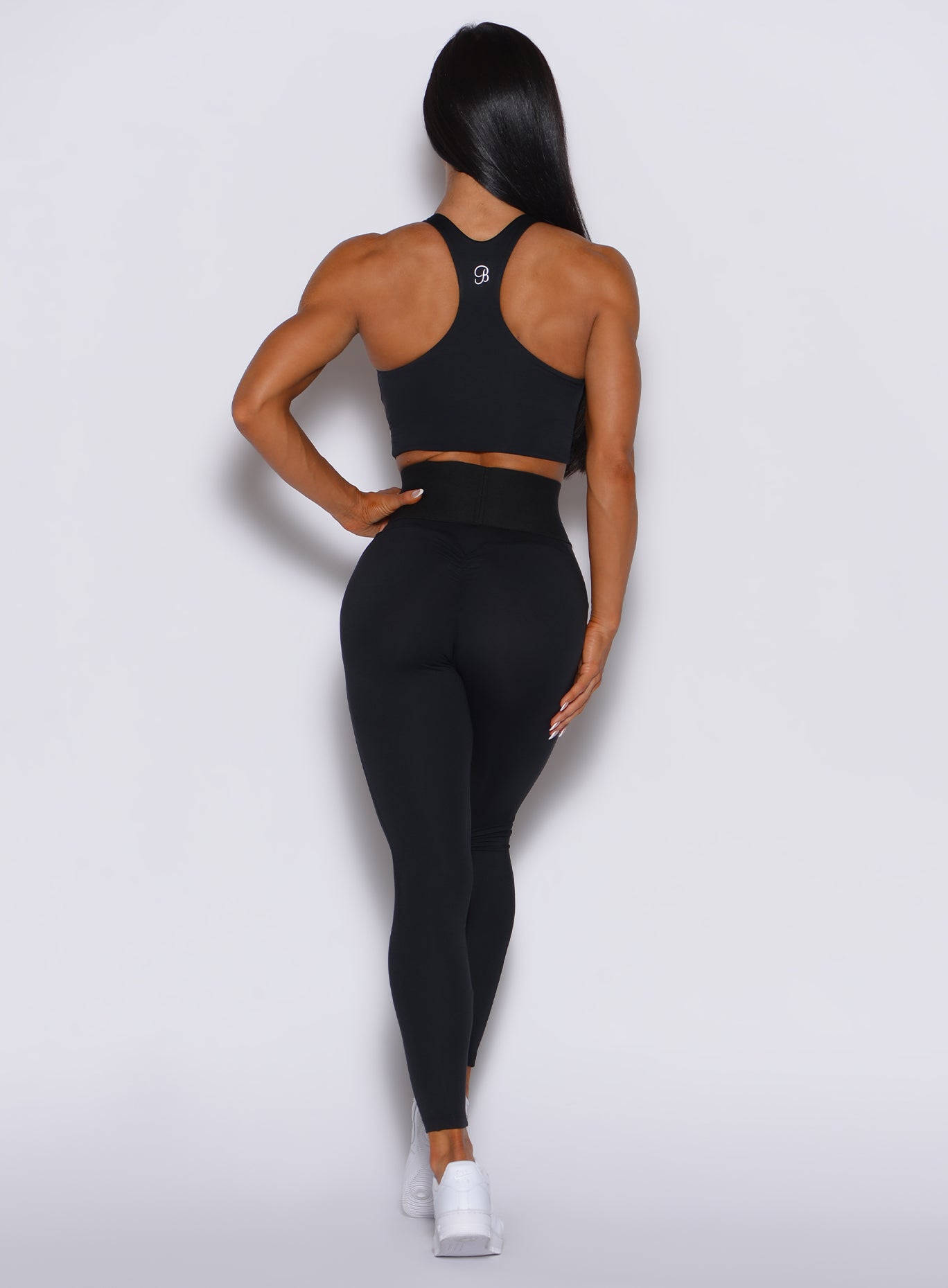 Back profile view of a model in our black cincher leggings and a matching bombshell top