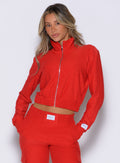 front profile view of a model wearing the Cloud Full Length Jacket in scarlet red color with the front zip closed. 