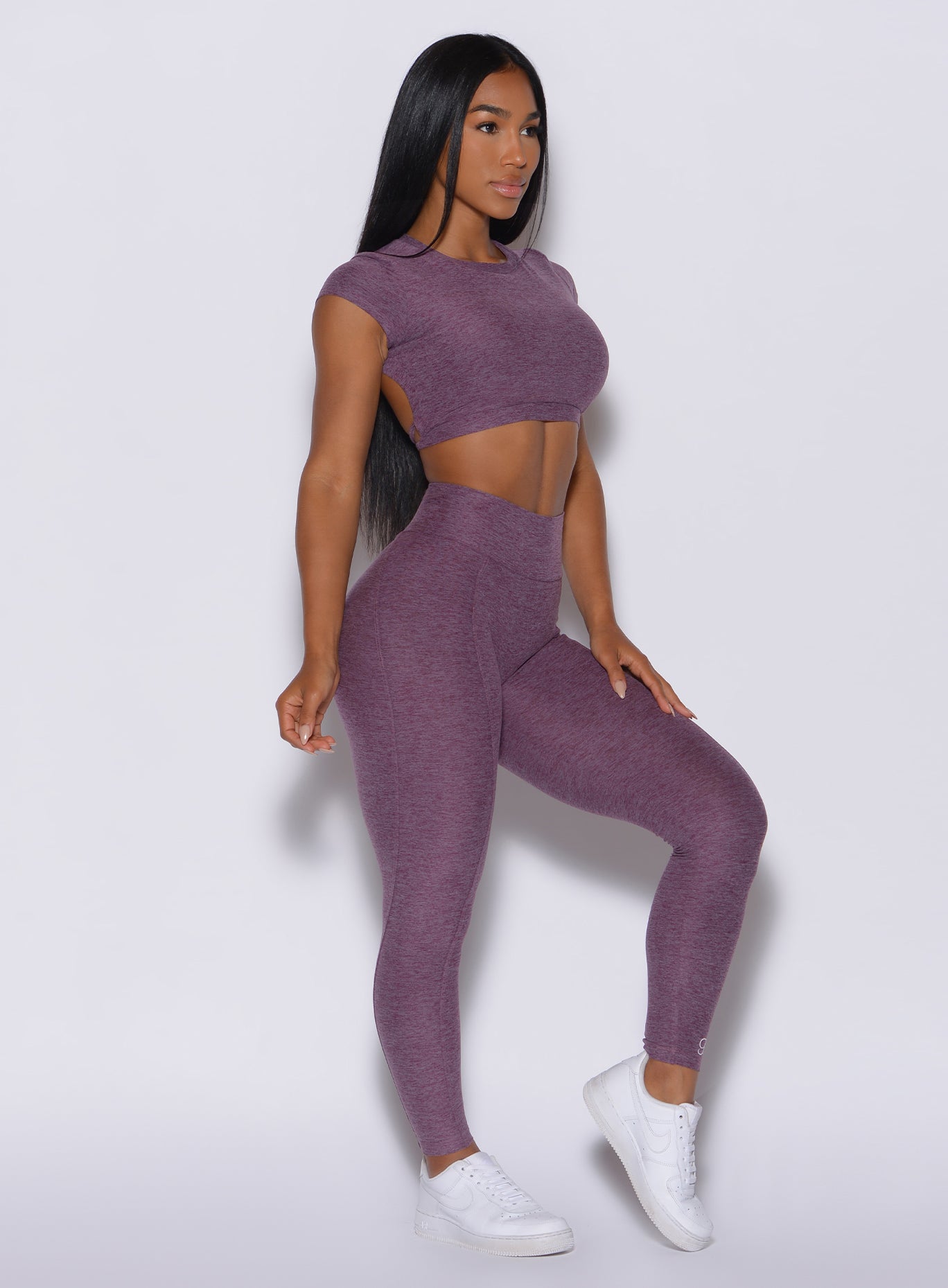 Right side profile view of a model angled slightly to her right wearing our cloud leggings in regal purple color and a matching sports bra