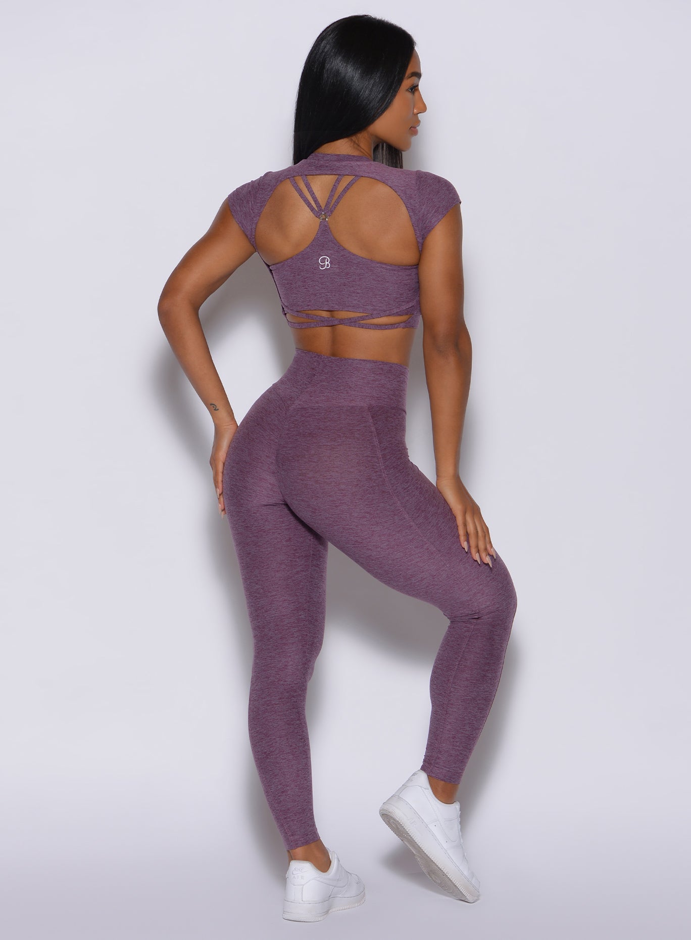 Back profile view of a model in our cloud leggings in regal purple color and a matching sports bra