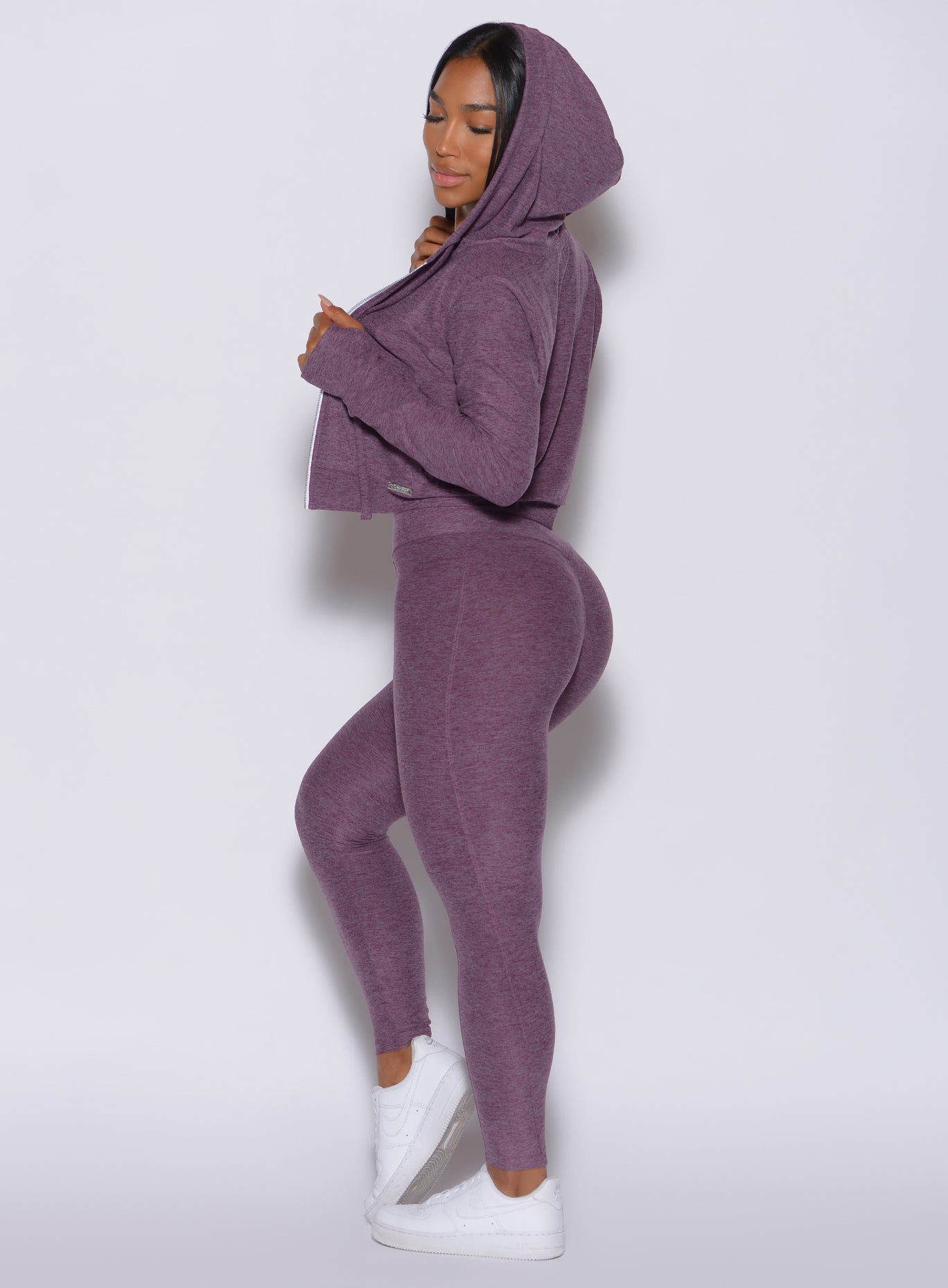 Left side profile view of a model in our cloud leggings in regal purple color and a matching hoodie