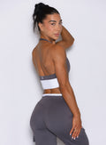 Right side view of model looking over shoulder wearing Bombshell Sportswear Confidence bra top in Champion Grey color, featuring sculpting supportive fit and open back design