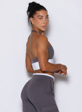 Right side profile view of model wearing Bombshell Sportswear Confidence bra top in Champion Grey color, featuring sculpting supportive fit and smooth stretch fabric