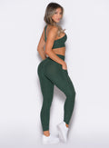 Right side profile view of a model facing to her right wearing Contour Leggings and the matching Cross Over Halter Bra in Pine color
