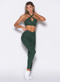front profile view of a model posing in our Contour Leggings and the matching Cross Over Halter Bra in Pine color