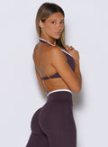right side profile view of a model wearing the Contrast Voltage Sports Bra in black orchid color